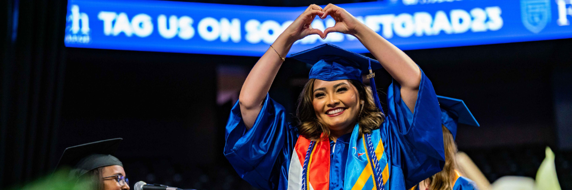 graduate walking across stage making heart with hands