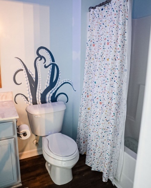 toilet with octopus decal on wall behind it